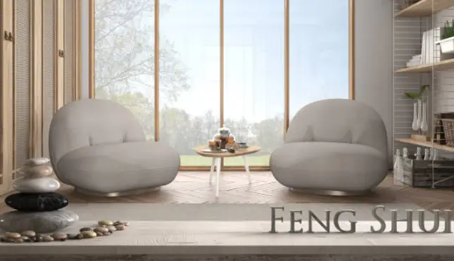 Salon zen inspiré du feng shui : deux fauteuils arrondis beiges devant une baie vitrée, table basse avec thé, galets et éléments naturels, bois clair
