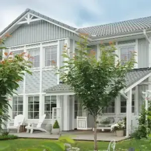 Maison scandinave gris clair à deux étages avec terrasse bois et jardin verdoyant, image d’inspiration maison bien-être