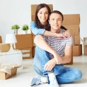 Couple assis au milieu de cartons de déménagement dans un intérieur lumineux, moment d’emménagement